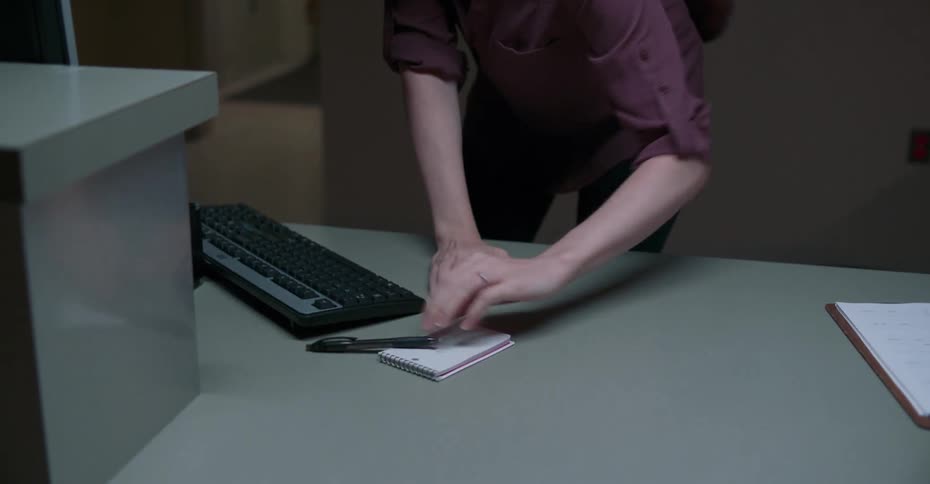 A woman working in an office scribbles a quick note in a notepad