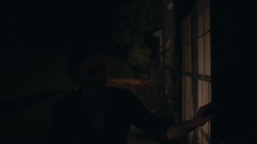 A person walks outside a house in the dark