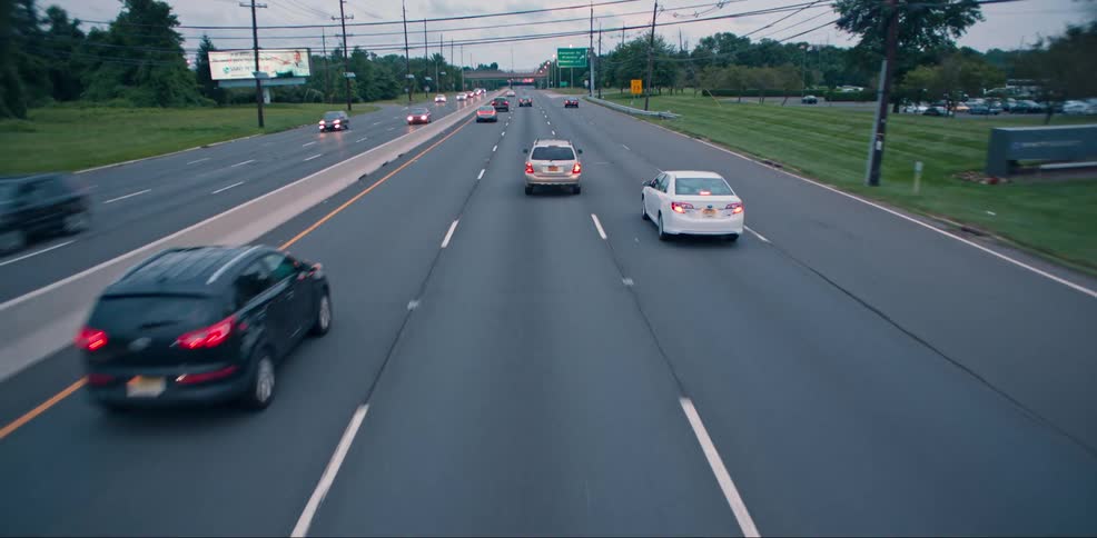 A car traveling in the center lane tries to move right but swerves back into its lane on a three lane highway