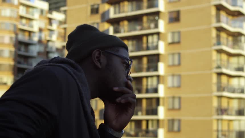 A man is standing on a rooftop looking at other buildings on a sunny day