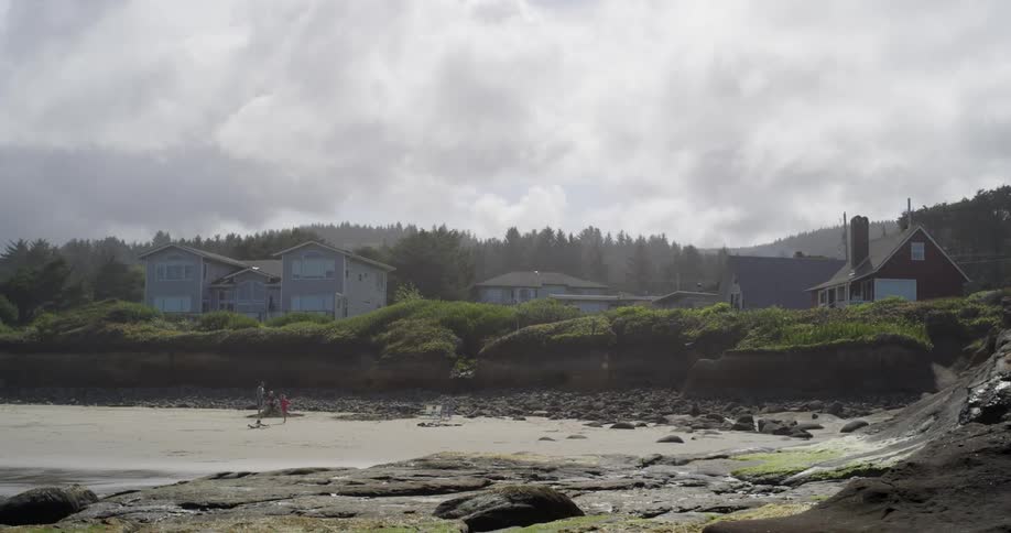 People stand on a beach with clouds overhead