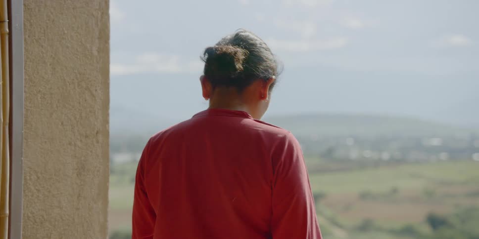 Woman stands on patio overlooking valley and hills