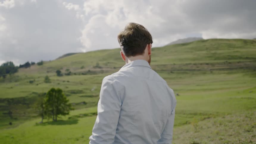 Man walks on the path through hills on a cloudy day
