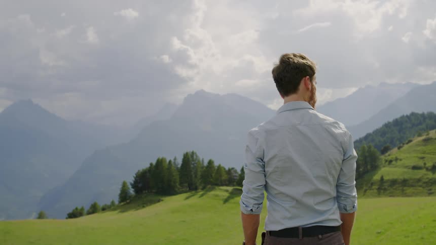 A young white man walks across a field