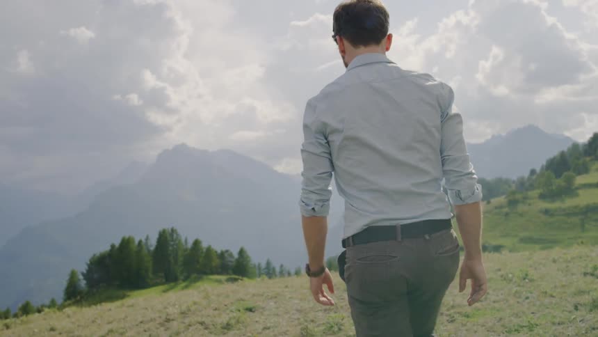 A man is walking in a grassland area outdoors