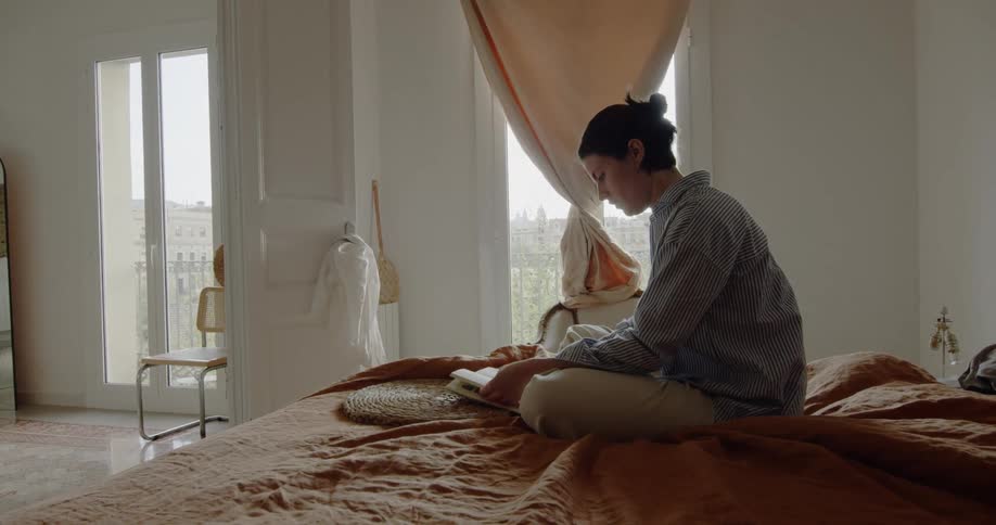 A woman reads a book in bed