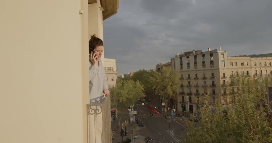 Woman talks on the smartphone in the balcony of the apartment