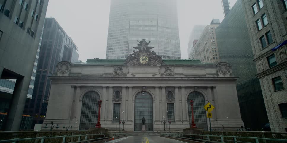 Person stands in front of a large building that has three arches