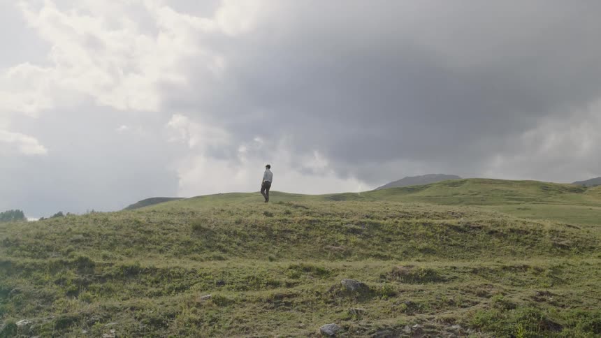 A man walks in a hilly field