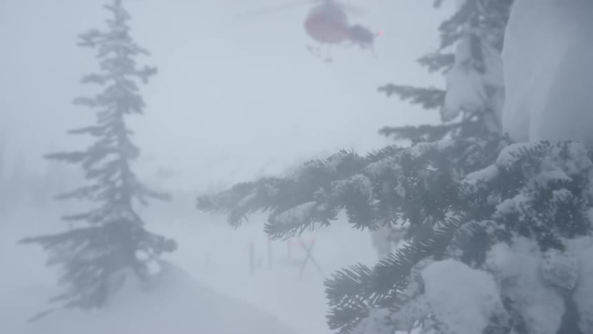 A helicopter flies above a snow covered tree