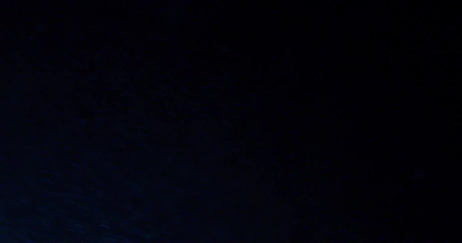 A light illuminates falling snow at night