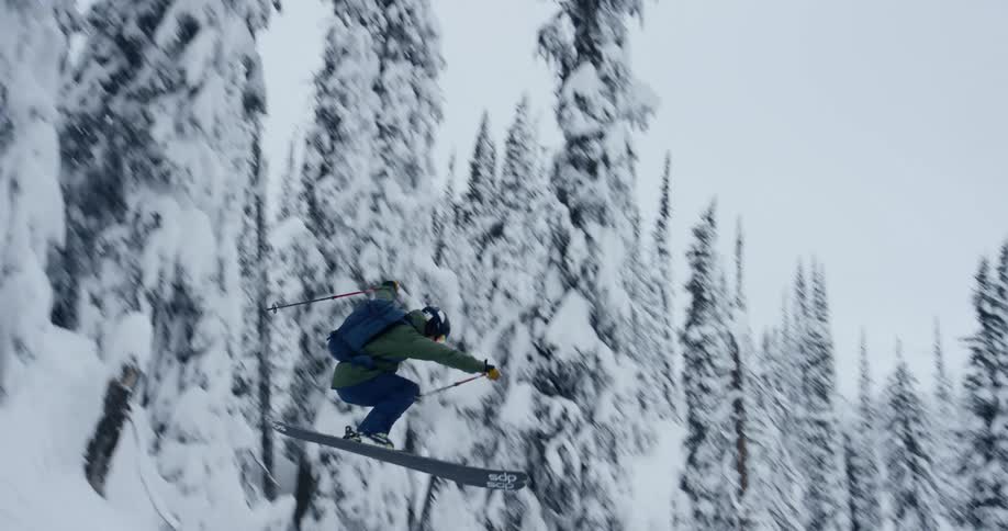 A skier launches off a large snow covered cliff