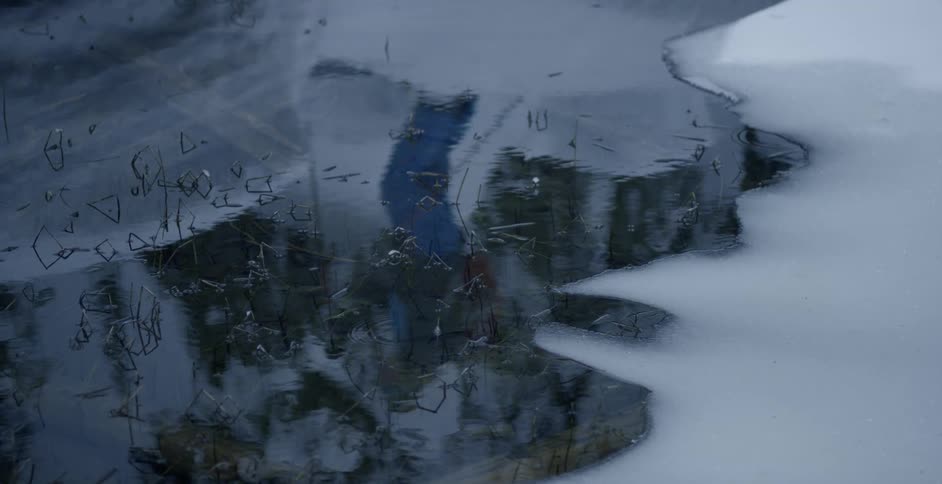 Reflection of cross country skier on a melted snow puddle
