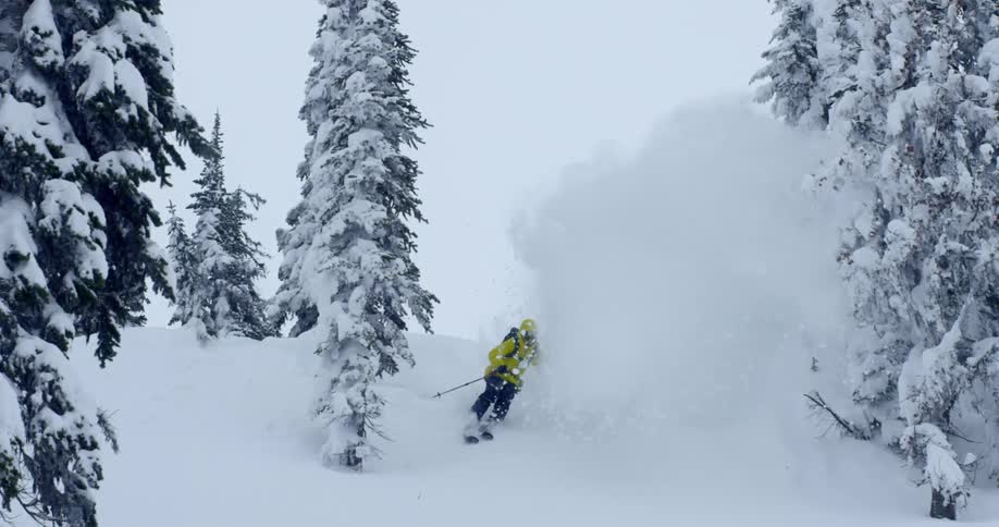 Man skiing through pines and down a steep mountain
