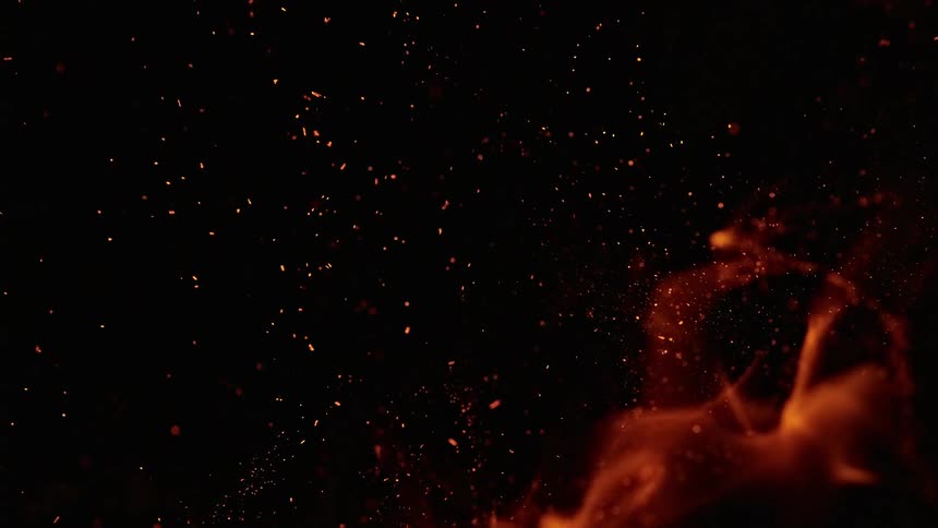Sparks float in air as flames dance against blackness