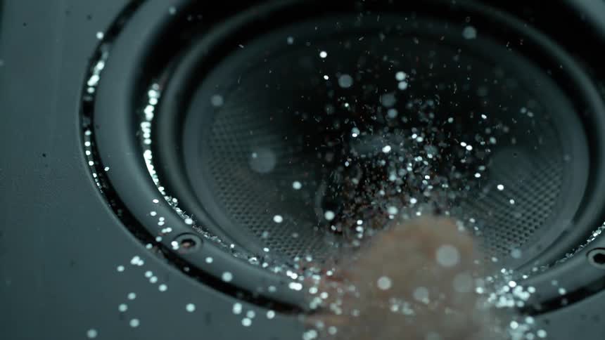 A speaker vibrates and shakes and blows clouds of glitter into the air