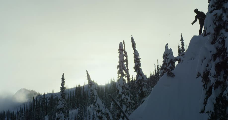 A man throws snow down a steep cliff
