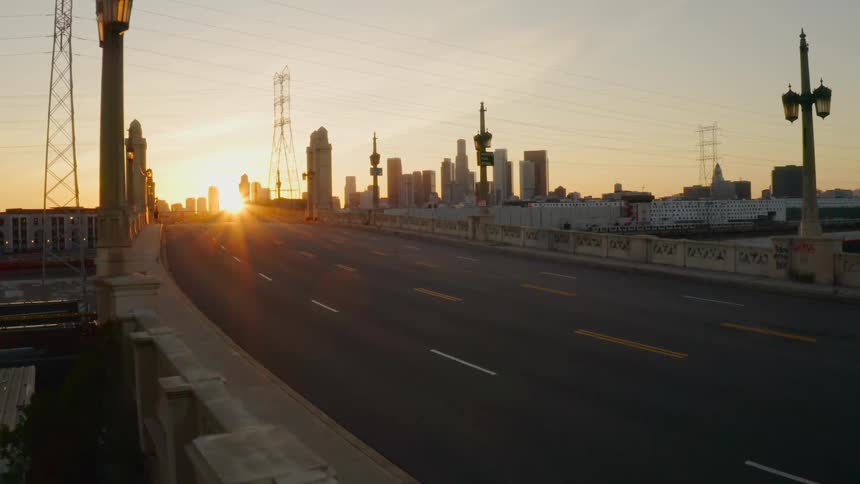 Camera zooms across empty bridge towards city skyline at dawn