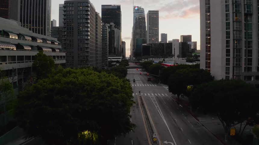 A wide street lined with skyscrapers running through a metropolis in the evening