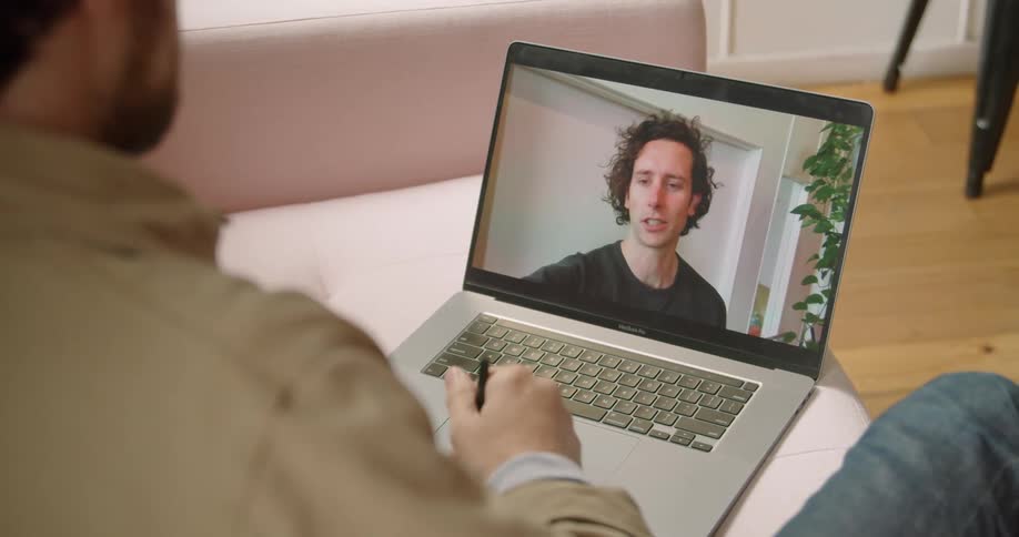 A man talks to another man on a video call on his laptop