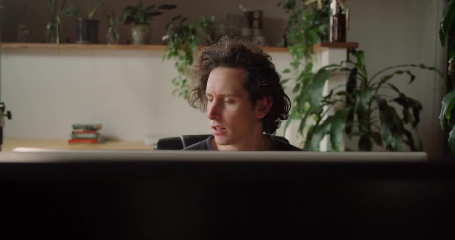 Man teleconferences sitting in room decorated with potted plants
