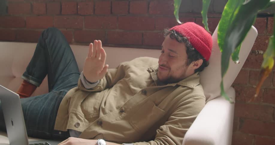 A white man types on a laptop while conversing