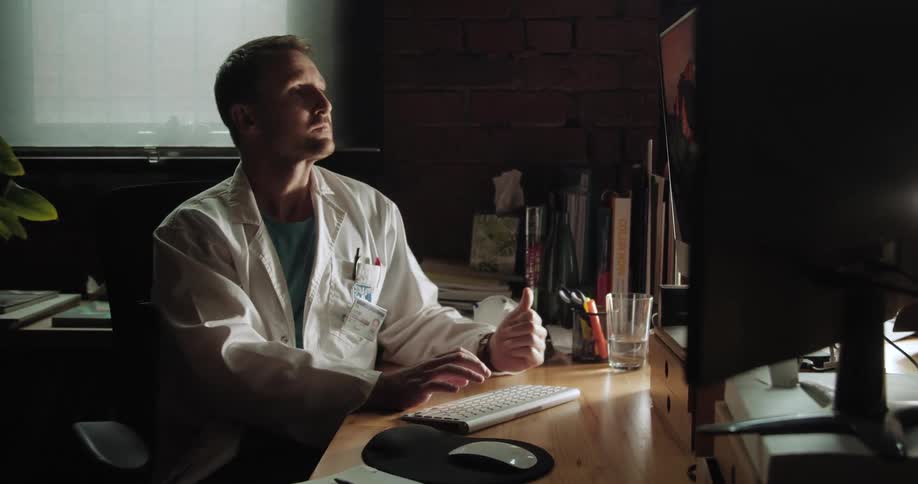 A doctor sitting at a computer distressed