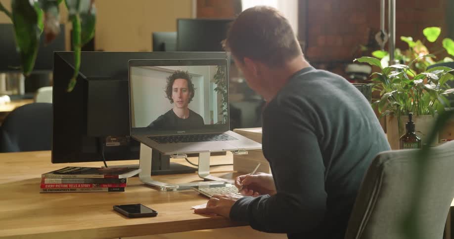 Man working at office talks to coworker on video conference