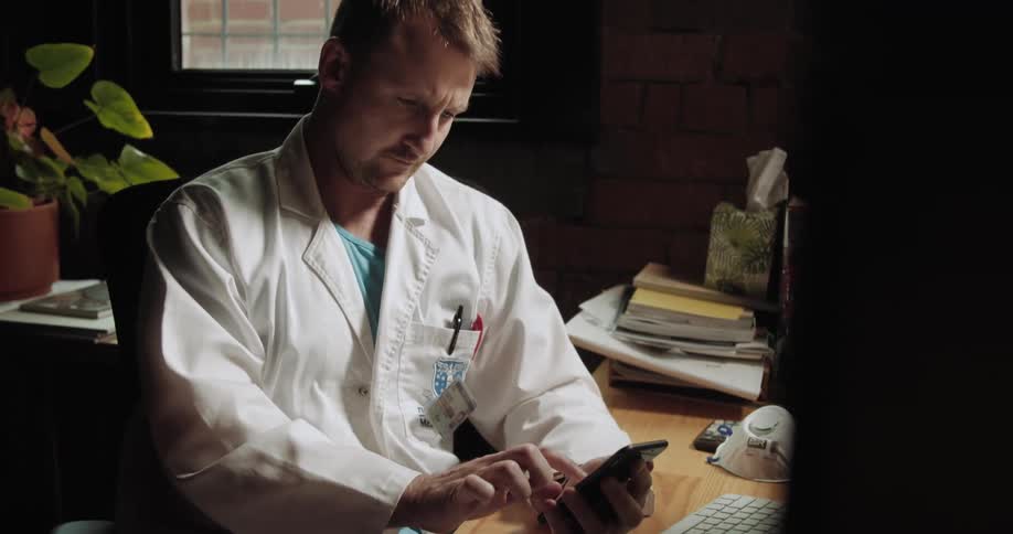 A doctor types on a smartphone