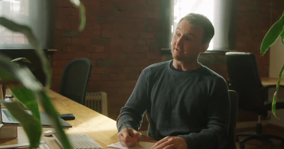 Man works at table making notes while conversing