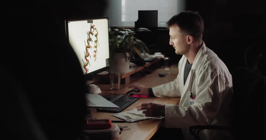 A person in a lab coat looks at dna on a computer screen
