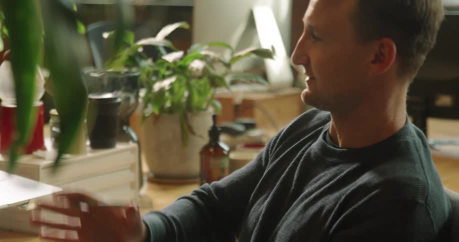A man gestures as he has a video call with another who is visible on the laptop screen