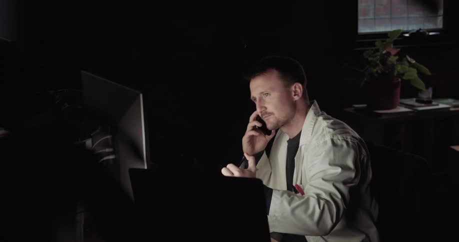 A doctor talks on a cell phone while pointing at a computer screen
