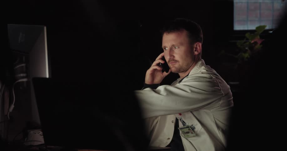 A doctor talks on the phone in front of a computer in an office