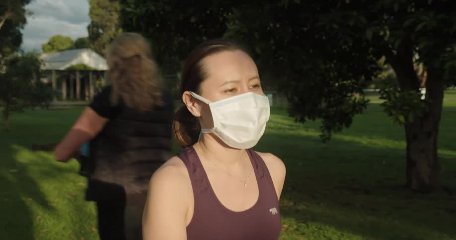 A woman wears a medical mask while walking through a neighborhood