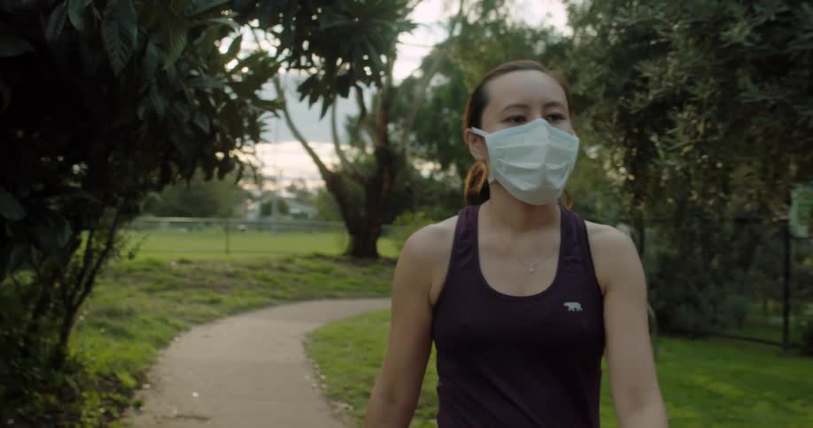 Asian woman wearing a face mask walks along the road in the public park