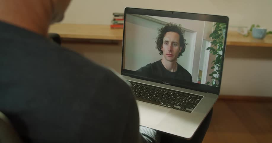 Two men videochat on a laptop