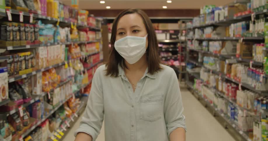 A woman wearing a mask walks through a grocery store