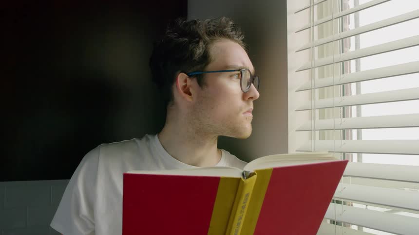 Man reads a book close to a window