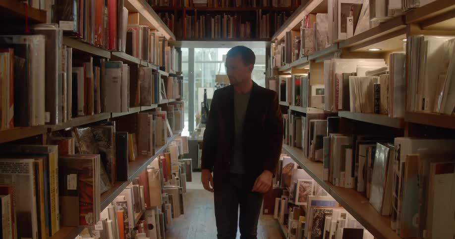 A man walks along the aisle in a library