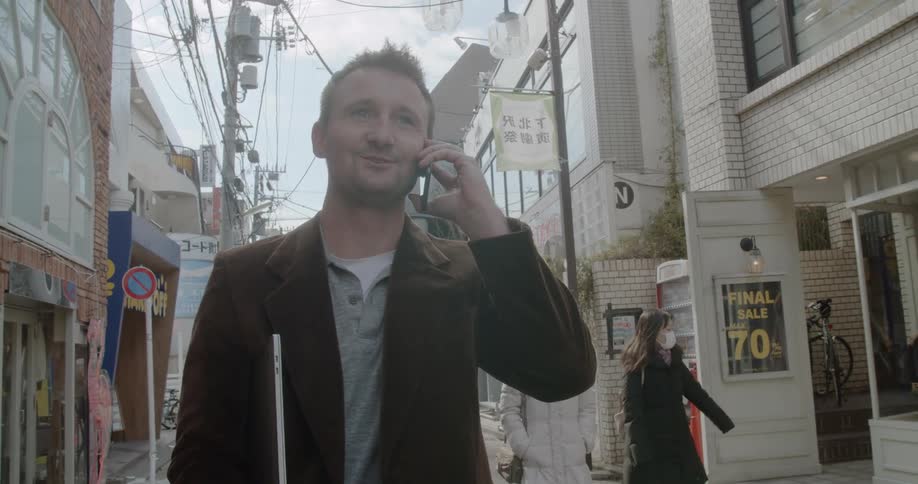 Man talks on a cell phone as he walks on a city street