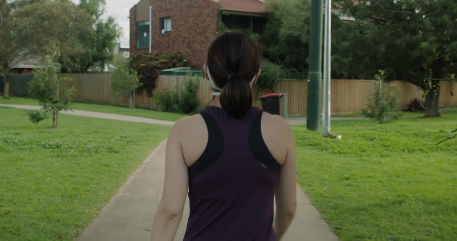 A woman walks down a path through a park