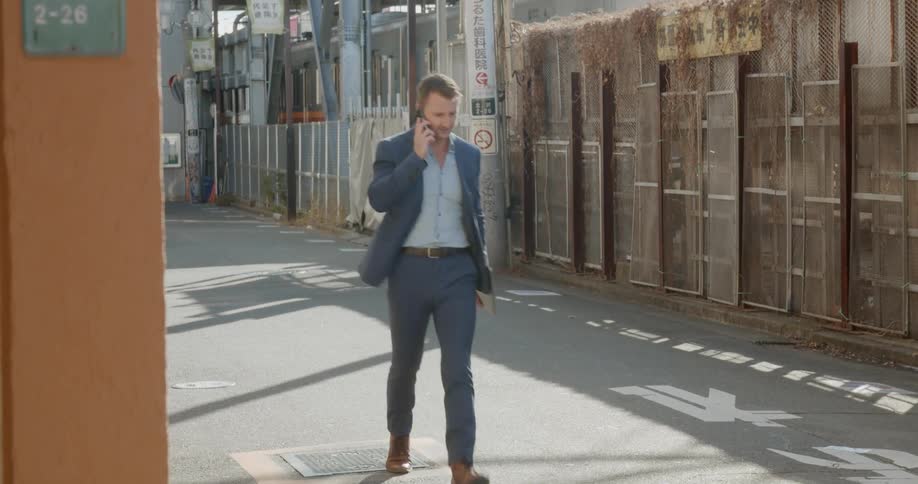 Man walks down the street while talking on a cell phone