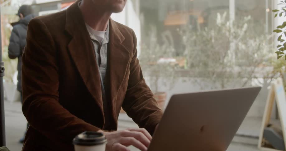 A man sitting at a table typing on a laptop