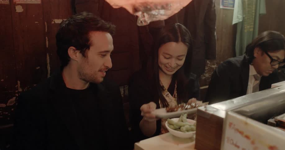 Woman reaches for a plate of food as she sits at a counter with other people