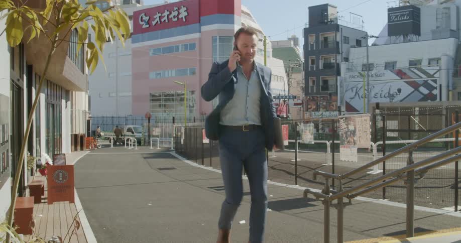 Man talking on cell phone walks through city downtown