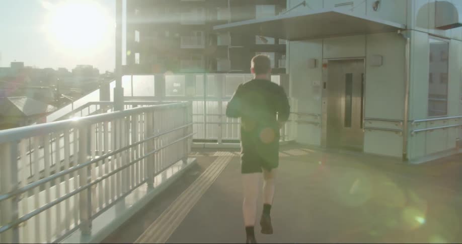 A man jogs on a pedestrian bridge and down a staircase