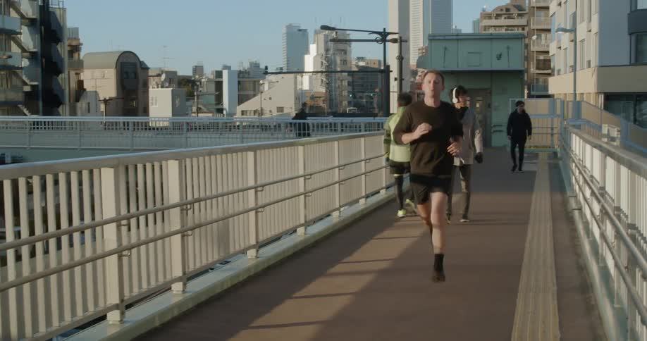 A man jogs down an elevated walkway in the city