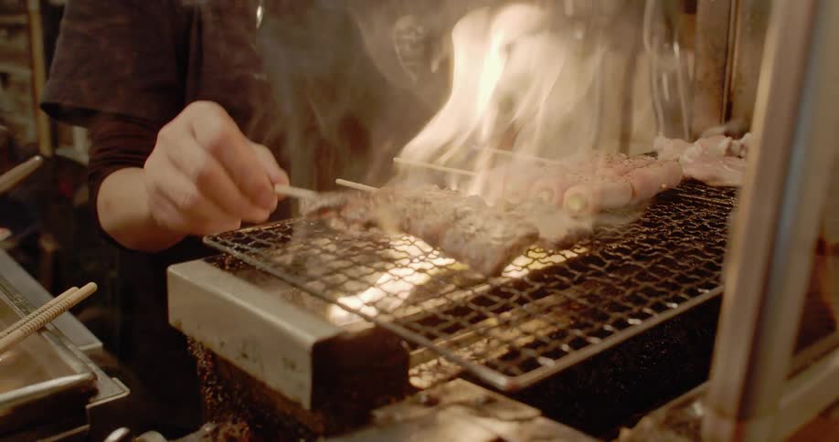 A person cooks meat on a grill