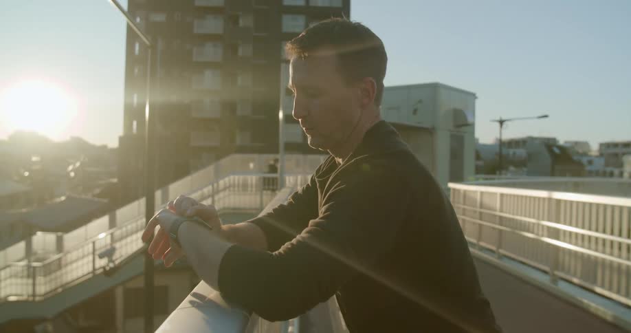 A man is standing on a bridge and checking his watch